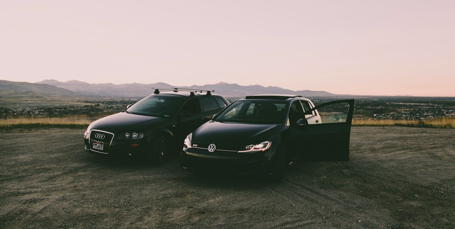 two black vehicles parked beside green grass