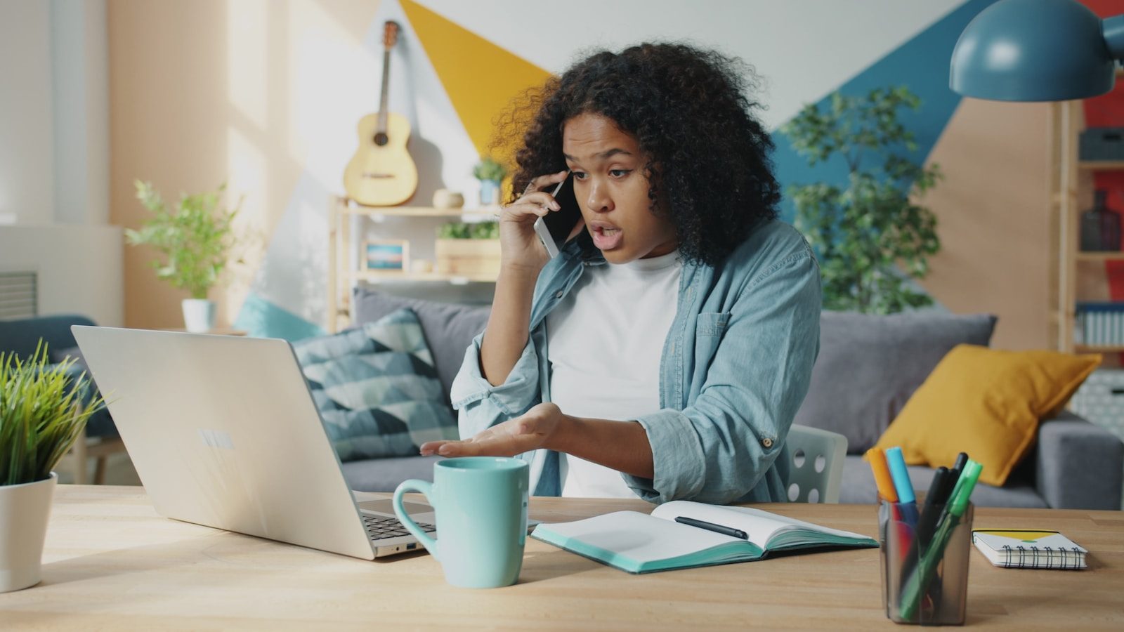 Young woman talking on phone at laptop desk